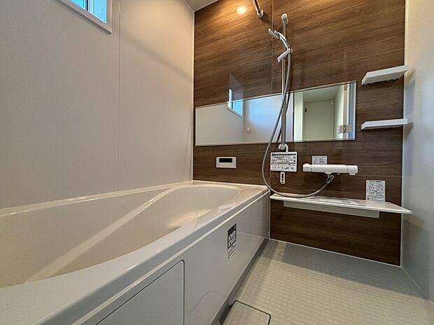 【浴室　A号棟現地写真】■リクシル　システムバスルーム「AX」。フロアはスポンジが奥まで入り掃除がラクラク。また独自の断熱層を使用しているため冬場でも冷やっとしません。