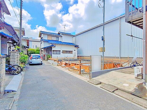 【前面道路含む現地写真】≪現地（2026年7月）撮影≫東側4mの私道に面した舗装道路。手前に整地された敷地と周辺住宅が並ぶ様子が確認でき、駐車2台対応のプランです。