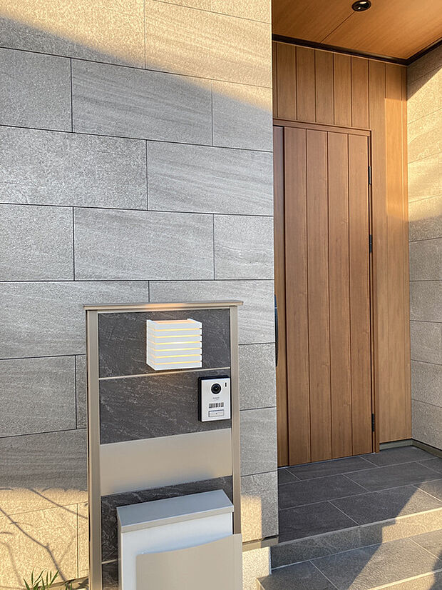 【玄関のタイルはアドヴァンのモルジュ】ライトグレーのタイルと木目調の玄関ドアの組み合わせがかっこいい。