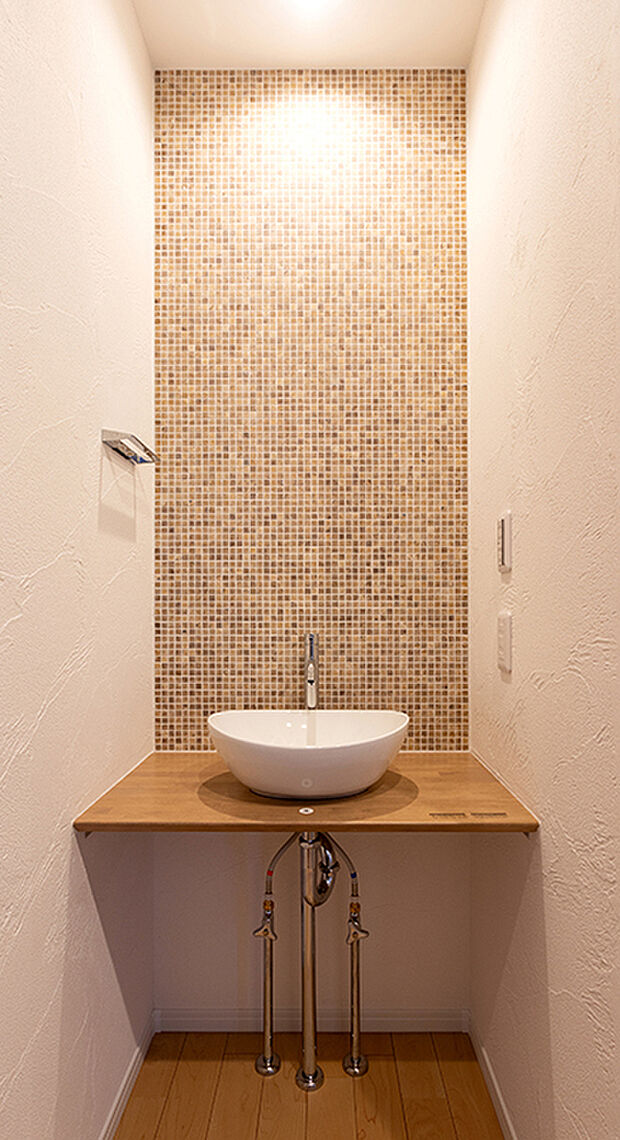 【1階手洗いコーナー 】メインの洗面室とは別に、玄関を入ってすぐのところにセカンド洗面台を設置。コロンとしたかわいらしい小型の洗面ボウルは、外から帰ってきてすぐに手洗いとうがいができるので、小スペースながら機能的!ウイルスはドアノブから感染につながることもあり、風邪や感染症などの予防になり、いつでも清潔な状態で室内へ。遊んで帰ってきた子供も自然と手洗いが習慣化され、来客時にはわざわざ洗面室を使って頂かなくて済みます。また、壁に施されたモザイクタイルは、遊び心が溢れるデザインでインテリアとしても楽しめると人気です。