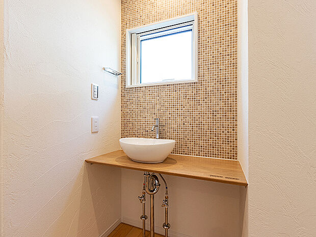 【-】メインの洗面室とは別に、玄関を入ってすぐのところにセカンド洗面台を設置。コロンとしたかわいらしい小型の洗面ボウルは、外から帰ってきてすぐに手洗いとうがいができるので、小スペースながら機能的!ウイルスはドアノブから感染につながることもあり、風邪や感染症などの予防になり、いつでも清潔な状態で室内へ。遊んで帰ってきた子供も自然と手洗いが習慣化され、来客時にはわざわざ洗面室を使って頂かなくて済みます。また、壁に施されたモザイクタイルは、遊び心が溢れるデザインでインテリアとしても楽しめると人気です。