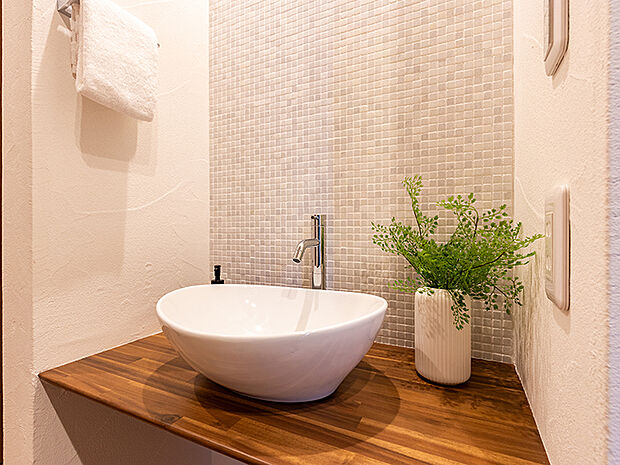 メインの洗面室とは別に、玄関を入ってすぐのところにセカンド洗面台を設置。コロンとしたかわいらしい小型の洗面ボウルは、外から帰ってきてすぐに手洗いとうがいができるので、小スペースながら機能的！ウイルスはドアノブから感染につながることもあり、風邪や感染症などの予防になり、いつでも清潔な状態で室内へ。遊んで帰ってきた子供も自然と手洗いが習慣化され、来客時にはわざわざ洗面室を使って頂かなくて済みます。また、壁に施されたモザイクタイルは、遊び心が溢れるデザインでインテリアとしても楽しめると人気です。