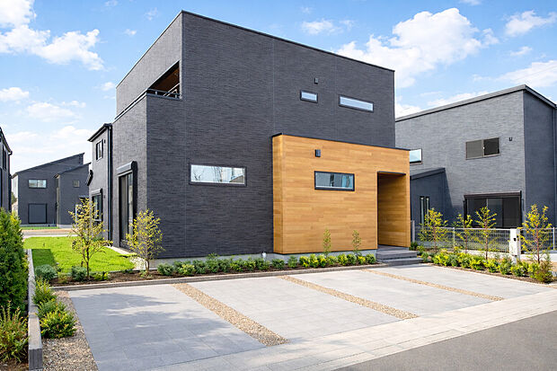 【外観施工例】重厚な外壁に温もりの木張りアクセント、光を取り込むスマート設計。