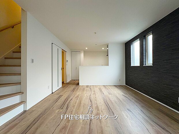 開放感あふれる明るいリビング。木目調の床と落ち着いたアクセントウォールが調和し、上質で心地よい空間を演出。家族の時間が自然と集まる居心地の良い場所です。