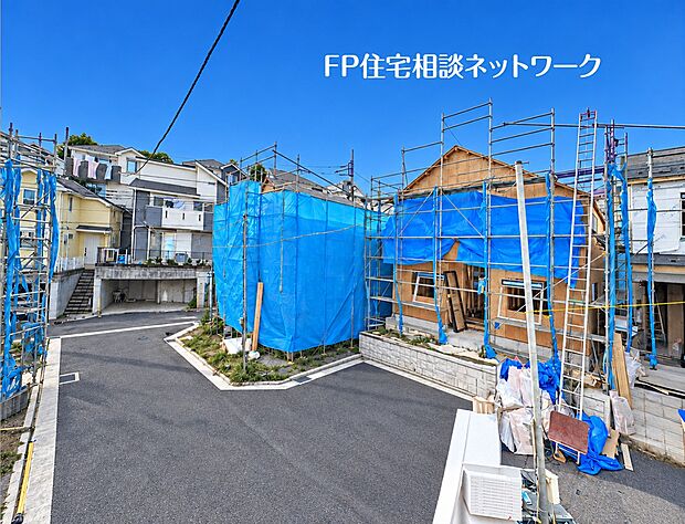 やや高い視点から見た現地の様子です。建築中の建物と敷地の形状、前面道路の配置がよく分かります。周囲の既存住宅街の雰囲気や、隣接する建物との距離感などの周辺環境が確認できます。