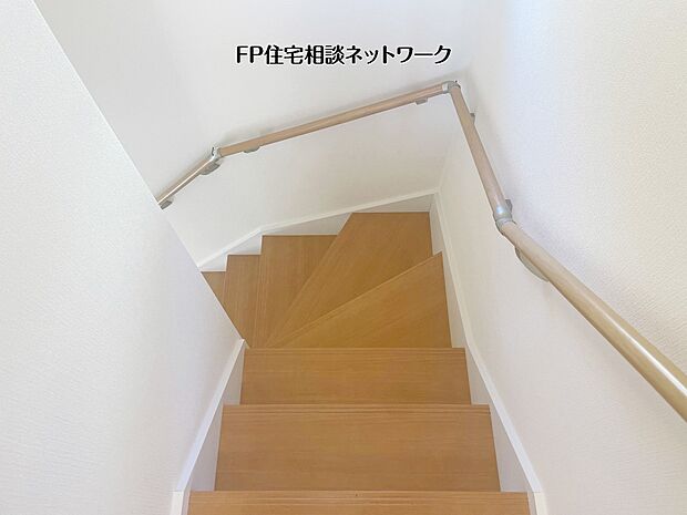 【その他内観】【階段】 木の温もりを感じる階段には、しっかりとした手すりを設置し、日々の昇り降りも安心です。白を基調とした壁面に木目が映えるシンプルなデザインで、住まい全体に統一感と落ち着きを与えてくれます。