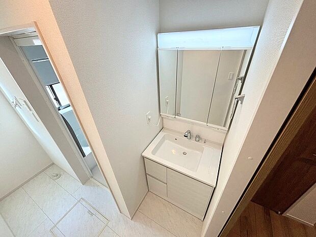 【洗面室】大きな三面鏡がついた洗面カウンターには、鏡の裏側にも収納スペースがありとても便利。シングルレバー混合栓にはシャワーの切り替えもあり、朝の身支度に大活躍です。