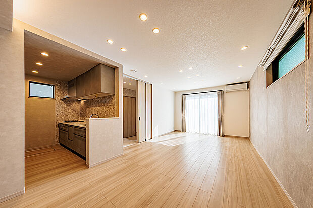 【リビングダイニング】T-2／開放的な大空間が、お互いの気配を感じられる豊かな時間をもたらします。柔らかな色調の内装と大きな窓から注ぐ陽光が、部屋全体を優しく包み込む明るく心地よい住空間です。