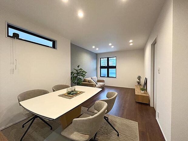 【【2号棟LDK/約16.2帖】】ダイニング・リビングスペースをゾーニングしやすい縦型のLDK。アクセントクロスやデザイン性のある窓を採用し、おしゃれな雰囲気が漂います。