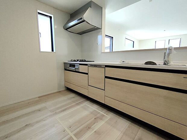 【キッチン(1号棟)】3口ガスコンロとレンジフードを備えた機能的なキッチン。シンクや収納も充実し、調理も片付けも快適。小窓から光が差し込む明るい空間で、毎日の料理が楽しくなる設計です♪
