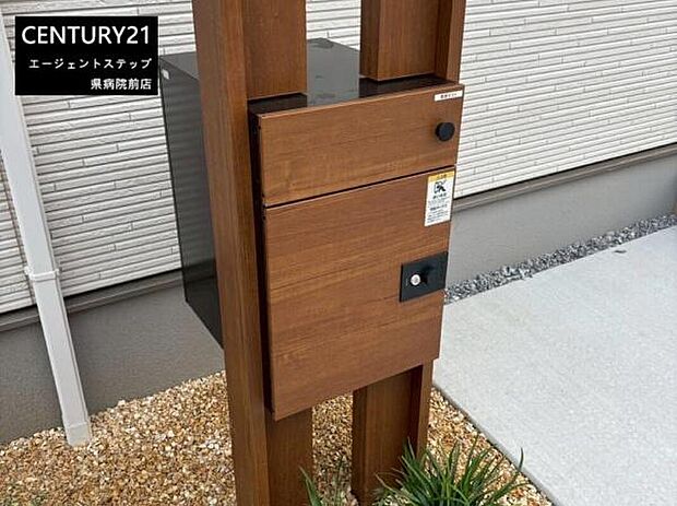 【ポスト】シンプルなデザインの宅配ボックスが設置されています。木目調の外観が周囲に調和しています。玄関まわりの印象を引き締めるアクセントとなっています。雨の日でも安心して荷物の受け取りが可能です。