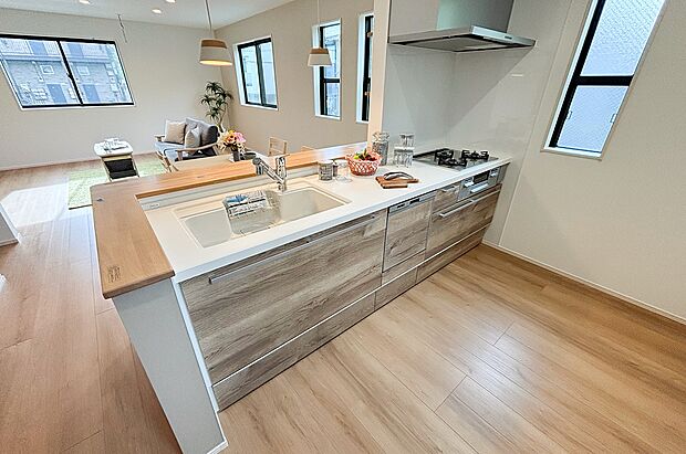 【キッチン】木目調がお洒落なキッチンはインテリアの主役。リビングの家族と会話が弾む対面式です。(1号棟)