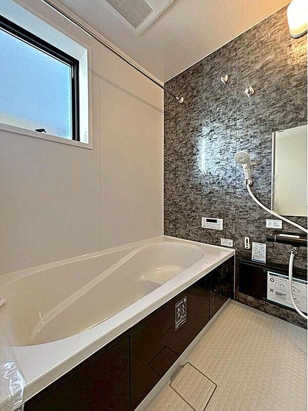 【浴室】１号棟
アクセントパネルで落ち着きのある雰囲気を演出したバスルーム♪毎日の疲れを癒やすバスタイムをお楽しみ下さい！浴室換気乾燥暖房機付きで、ジメジメした季節や雨の日には、浴室内干しも可能！