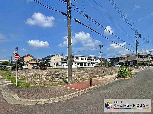 【現地外観写真】歩道や舗装道路に面しているため落ち着いた住宅地の雰囲気が感じられます。周辺は低層住宅が並び、青空と陽射しが映える日当たりの良い印象です。