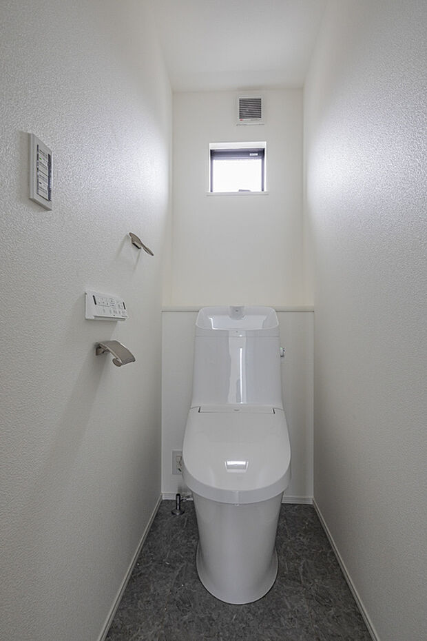 【トイレ】白を基調にした清潔感あふれるトイレ空間。小さな窓から自然光が入り、明るく心地よい雰囲気を演出します。奥行きのあるレイアウトで狭さを感じにくく、シンプルながら使いやすい設計が魅力。毎日使う空間だからこそ、落ち着きと清涼感にこだわっています。