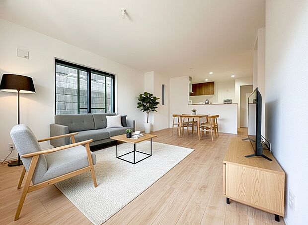 窓から溢れる柔らかな陽光が、温かみのある木目調のフローリングを優しく照らす、明るく開放的なリビングです。白を基調とした内装が光を拡散し、お部屋全体をいっそう広々と感じさせてくれます。