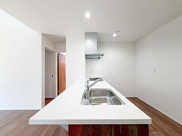 【キッチン】大きな白い天板が印象的な、作業スペースが広々としているため、複数人での料理や、お子様とのパン作りなども快適に楽しめます。リビング全体を見渡せる開放的な設計です。