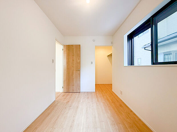 【洋室】ナチュラルな木目調のフローリングと白壁が調和した、明るく清潔感あふれる居室です。窓からは柔らかな自然光が差し込み、毎朝を爽やかな気分で迎えられます。