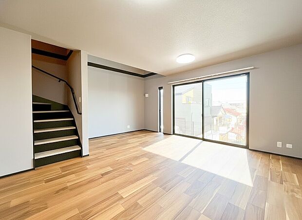 【リビング】二面採光のデザイン窓から差し込む暖かな光が、お部屋の隅々まで心地よく届けます。木の質感を活かしたフローリングと、洗練されたグレーの壁紙が調和し、北欧モダンな家具も映える上質な空間に仕上がっています。