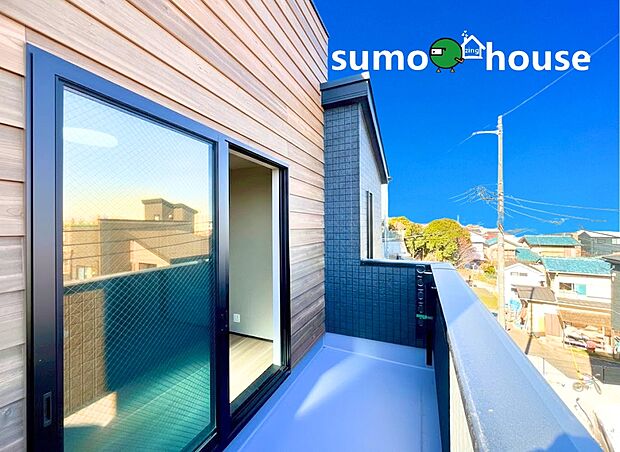 【落ち着いた住環境】木の温もりを感じさせる木目調の外壁と、モダンな黒のサッシが調和したスタイリッシュなバルコニーです。奥行きがあり、椅子を置いてのティータイムや、洗濯物干しなど多目的に活用できます。