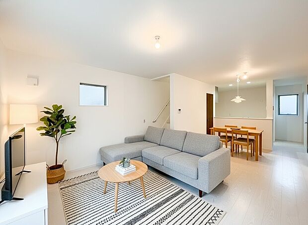 【リビング】白を基調とした内装と明るいフローリングが、空間をより広々と演出。キッチンはカウンター越しで家族との会話も弾みます。リビングイン階段で家族の繋がりを感じられる設計。