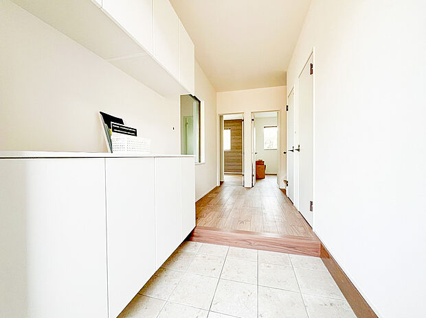 【玄関】一歩足を踏み入れると、奥行きのある廊下まで視線が抜ける開放的な設計が魅力です 。清潔感のある白い空間に、木目調のフロアが温かみを添え、家族を優しく迎え入れます 。