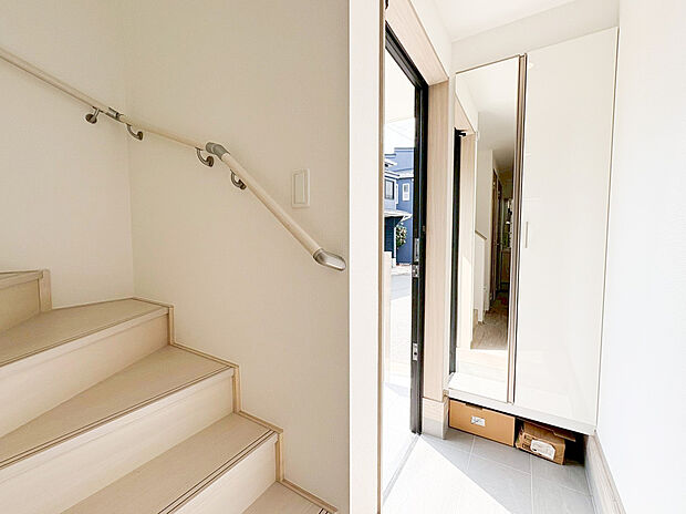 【玄関】リビングとの一体感を感じさせる、スタイリッシュなデザインの階段エリア 。光が隅々まで届く明るい設計が、毎日の移動を心地よいものにしてくれます 。住まい全体の清潔感をより一層引き立てる仕上がりです。