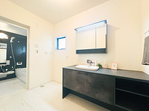 【広々洗面化粧台】ワイドなカウンターが目を引く、スタイリッシュなデザイン洗面台です。ベッセル式の洗面ボウルとシックなダークカラーの面材が、まるでホテルのような上質な雰囲気を演出します。