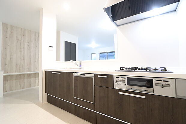 【浄水器、食洗器付きシステムキッチン　３号棟】三口コンロで料理の幅を拡げてくれる使いやすいシステムキッチンを採用。洗い場も大きいので野菜や食器を洗ったりする際にも捗り、奥様の強い味方となってくれるはずです。