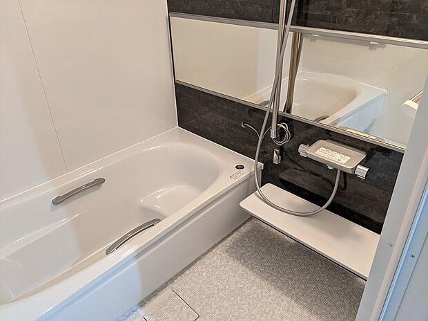 【くつろぎの時間を叶える浴室参考画像(インダストリアルハウス)】シンプルで清潔感のあるユニットバス。ゆったりとした浴槽は一日の疲れをしっかり癒してくれます。お手入れしやすい素材を採用し、日々の掃除もスムーズ。手すり付きで安全面にも配慮されており、幅広い世代に安心してご利用いただけます。落ち着いたカラーで統一された空間は、リラックスできるバスタイムを演出。機能性と快適性を兼ね備えた浴室です。