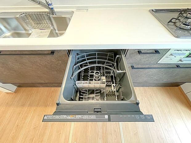 【引き出し式食洗機のあるキッチン】シンク横のカウンター下が開いた引き出し式の食器洗い乾燥機。隣にガスコンロと作業スペースが写っています。