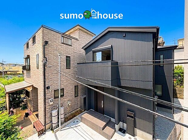 【青空に映えるモダンな邸宅】スタイリッシュなダークトーンの外観が目を引く住まい。手前にはゆとりあるスペースが確保されており、開放感があります。宅配ボックスも完備され、日々の暮らしやすさも快適です。