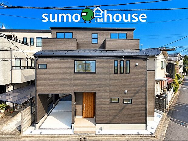 落ち着いたブラウン系の外壁と木目調の玄関ドアが調和したモダンな外観。存在感のあるフォルムとすっきりしたデザインが、洗練された印象を演出します。