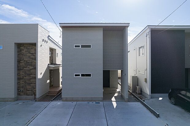 落ち着いた色合いの外壁に、木目調の軒天がアクセントを添える外観です。建物正面から玄関まわりの様子も確認できます。