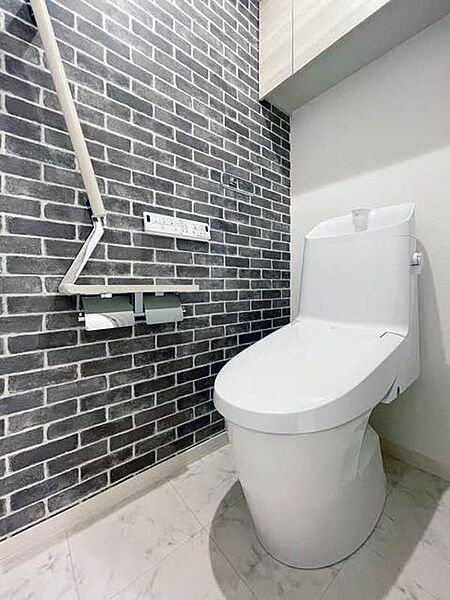 画像10:【トイレ】おしゃれなタイル調のアクセントを効かせたトイレ。上部吊戸棚、手摺、小物置きに使えるペーパーフォルダー天板があり、機能的にも充実しています。