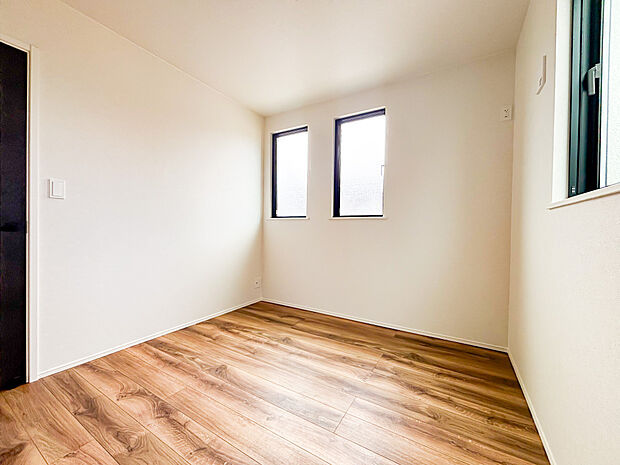 陽光差し込む明るい洋室。木目調フローリングと白壁が清潔感を演出し、心地よいプライベート空間でございます。