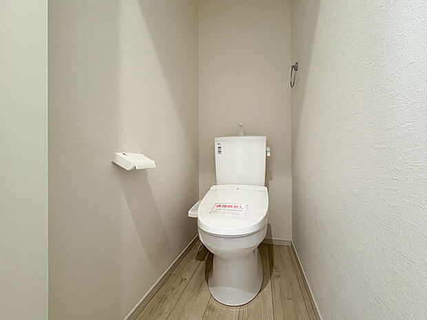 清潔感あふれる温水洗浄機能付きトイレ。 木目調の床で、明るく居心地の良い空間。