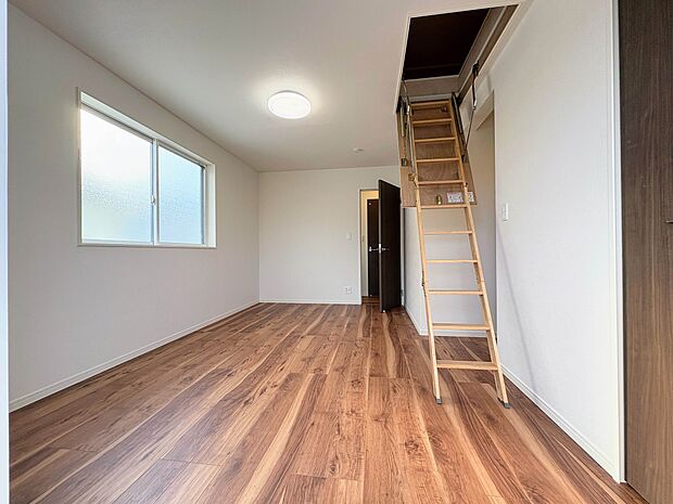 ロフトへのはしごが特徴的な洋室は、お子様の遊び場や収納スペースとしても活躍します。明るい窓から光が差し込み、木のぬくもりを感じるフローリングが心地よい空間です。