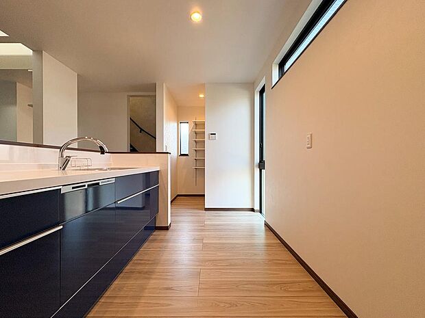 洗練されたネイビーキッチン。喚起窓や食洗機も完備。キッチン奥には収納棚付きのパントリーが。