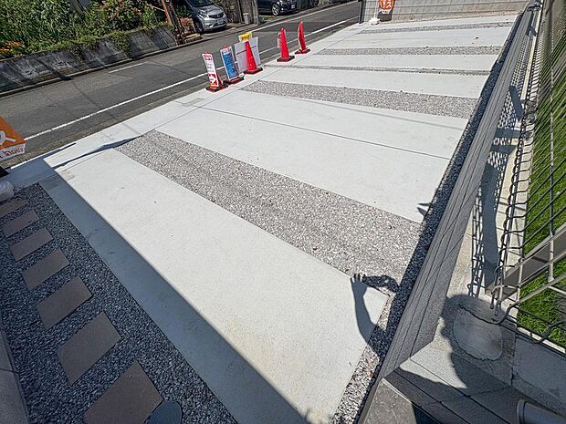 広々とした駐車場は、ご家族の車を複数台停められ、来客時も安心です。砂利とコンクリートの組み合わせが、物件の外観に洗練された印象を与えます。