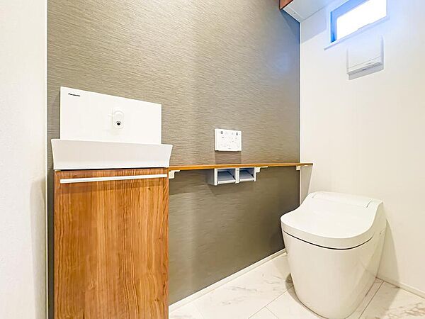 温水洗浄便座完備のトイレスペース。ついつい考え事をしてしまうほど落ち着く空間です。上部に収納棚がございます。手洗器も完備。2026/4/2撮影