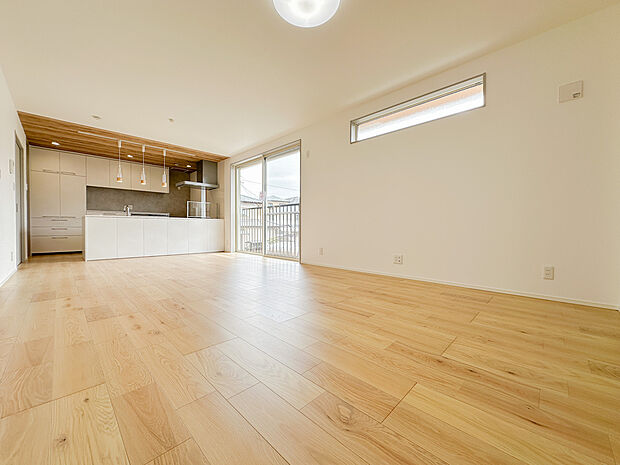 キッチンと一体感のある広々リビング空間。木目の床が温かみを演出し、窓からの採光で明るく開放感のある住まいを実現しています。