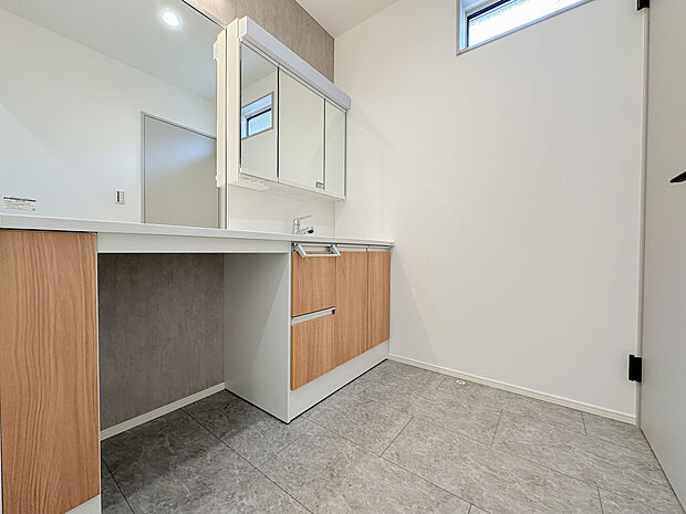 ゆとりある広さを確保した洗面スペース。三面鏡収納付きで身支度もスムーズに行えます。床材は水に強く、お手入れのしやすさにも配慮された使い勝手の良い空間です。