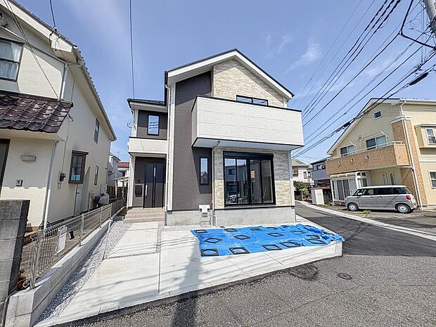 陽光が降り注ぐ、スタイリッシュな新築戸建て。ツートンカラーの外壁が目を惹き、家族の笑顔が溢れる明るい毎日を彩ります。