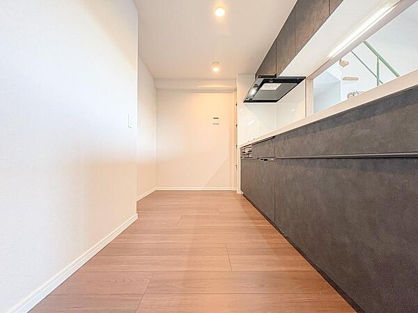 洗練されたダークグレーのキッチンは、広々カウンターで家事効率もアップ。リビングと繋がる開口部が家族の会話を育みます。機能性とデザイン性を兼ね備え、家族の笑顔が生まれる空間です。