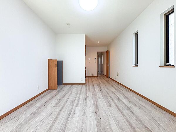 明るい陽光が差し込む、開放感あふれる室内。白い壁と温かみのある木目調フローリングが、家族の穏やかな時間を育みます。お子様ものびのびと過ごせる広々とした空間です。