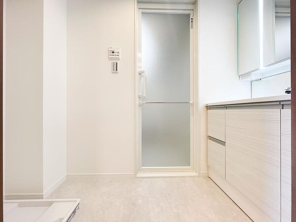 明るい大理石調の床材が演出する落ち着きのある洗面室。パナソニック製の洗面台や洗濯機置き場、浴室への動線がコンパクトに集約されています。白で統一された空間は、日々の家事時間を爽やかで快適なものにします。
