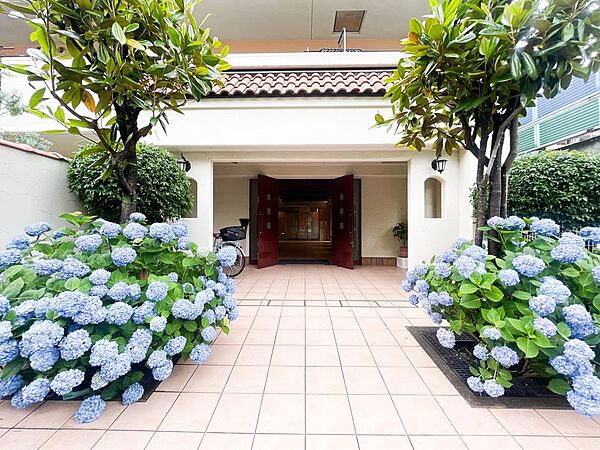 鮮やかな紫陽花と美しい植栽の緑に彩られた、南欧風の瓦屋根が印象的なエントランスアプローチ。優雅に開かれた風格ある扉と、綺麗に敷き詰められたタイルが、住まう方やゲストを心地よく出迎えます。