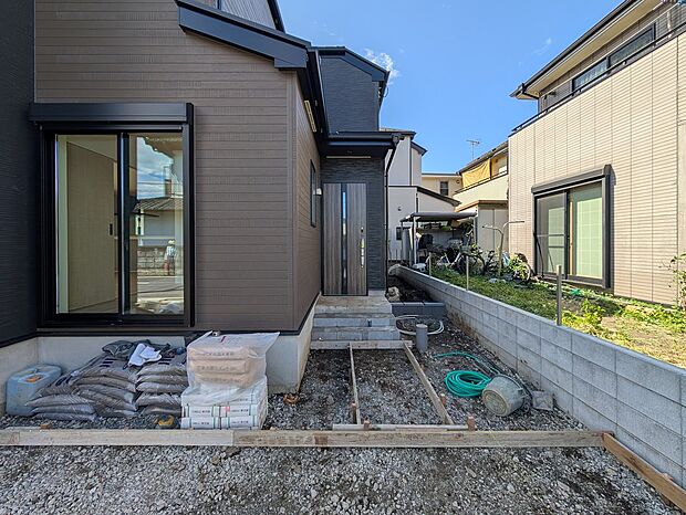黒と木目の対比が美しいエントランスアプローチ。重厚感のあるドアが住まいの質感を高めます。