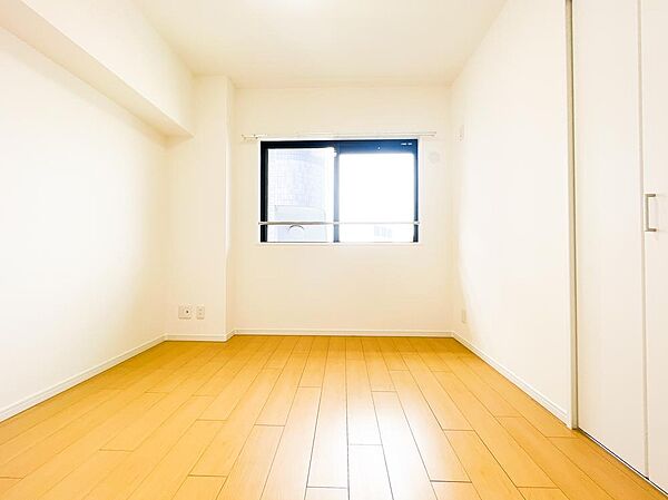 白を基調としたクロスに温かみのあるフローリングが調和したシンプルな洋室。大きめの窓から優しい自然光が広がり、勉強机やベッドなどの家具も自由にレイアウトしやすいため、お子様部屋や書斎に最適です。